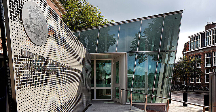 Foto von Referenzobjekt: „Amerikanische Botschaft in Amsterdam“, zeigt moderne Hochsicherheitsfenster und -türen in repräsentativem Gebäude.